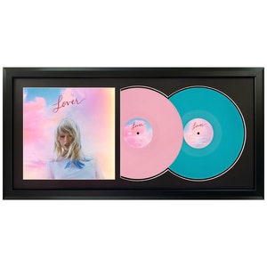 May include: A black framed double record display with a pink and turquoise vinyl record set. The album cover features a woman with blonde hair against a pink and blue sky with the word "Lover" written in cursive.