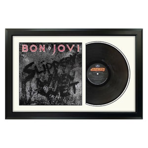 May include: A framed black vinyl record with a white mat. The record is by Bon Jovi and the album title is "Slippery When Wet".