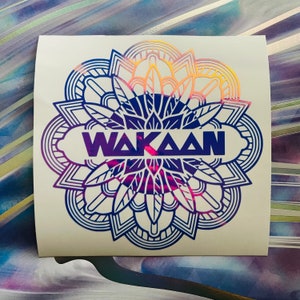 May include: A blue and pink mandala design with the word "WAKAAN" in the center. The mandala is a circular pattern with intricate details.