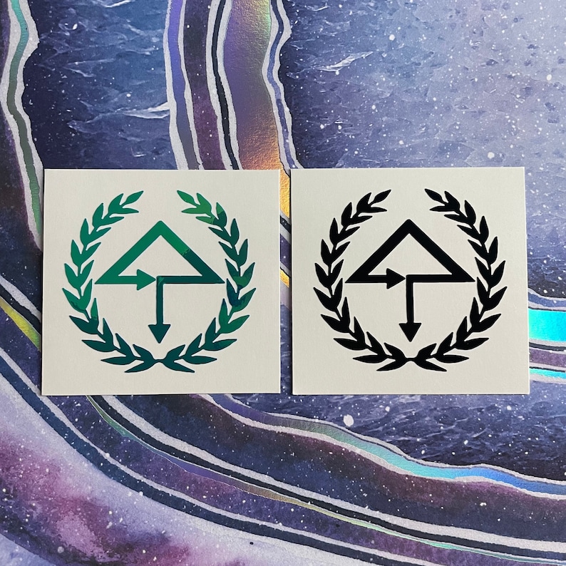 May include: Two square stickers with a black and green design. The design features a triangle with an arrow pointing to the right, a vertical line, and an arrow pointing down. The design is surrounded by a wreath of leaves.