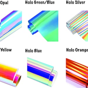 K&ouml;nnte beinhalten: Sechs Rollen holografisches Vinyl in verschiedenen Farben: Opal, Gr&uuml;n/Blau, Silber, Gelb, Blau und Orange. Das Vinyl ist aufgerollt und die Enden sind sichtbar.