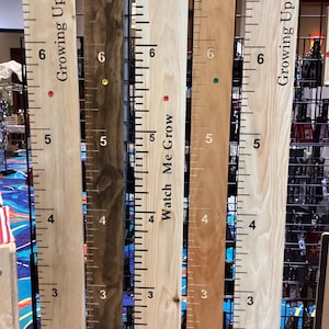 May include: Wooden growth charts with ruler markings and the phrases "Growing Up" and "Watch Me Grow". The charts are in various wood tones, with red, green, and yellow dots marking height increments. Each chart is approximately 6 feet tall.