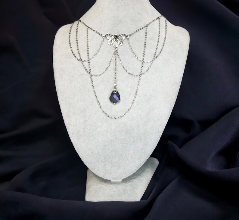 May include: A silver choker necklace with multiple chains and a dangling dark purple crystal pendant.