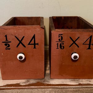 May include: Two rustic, open-top wooden boxes with a reddish-brown finish. Each box has black numbers and a white knob. The text on the boxes reads "1/2 X 4" and "5/16 X 4".