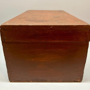 May include: A rectangular wooden box with a hinged lid. The box is stained a dark reddish-brown color, with visible wood grain and some wear. The box appears to be vintage or antique, and is likely used for storage or display.