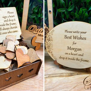 May include: Wooden guest book alternative with a box of heart-shaped wooden pieces and a sign that reads "Please sign a heart and drop it inside the frame." Another sign says "Best Wishes for Morgan."