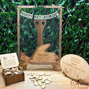 May include: A wooden retirement party sign with a clear frame, a wooden box filled with small wooden fish, and a wooden sign with the text "Please write your Best Wishes for Adam on a chip and drop it inside the frame." The sign has a small illustration of a person fishing.