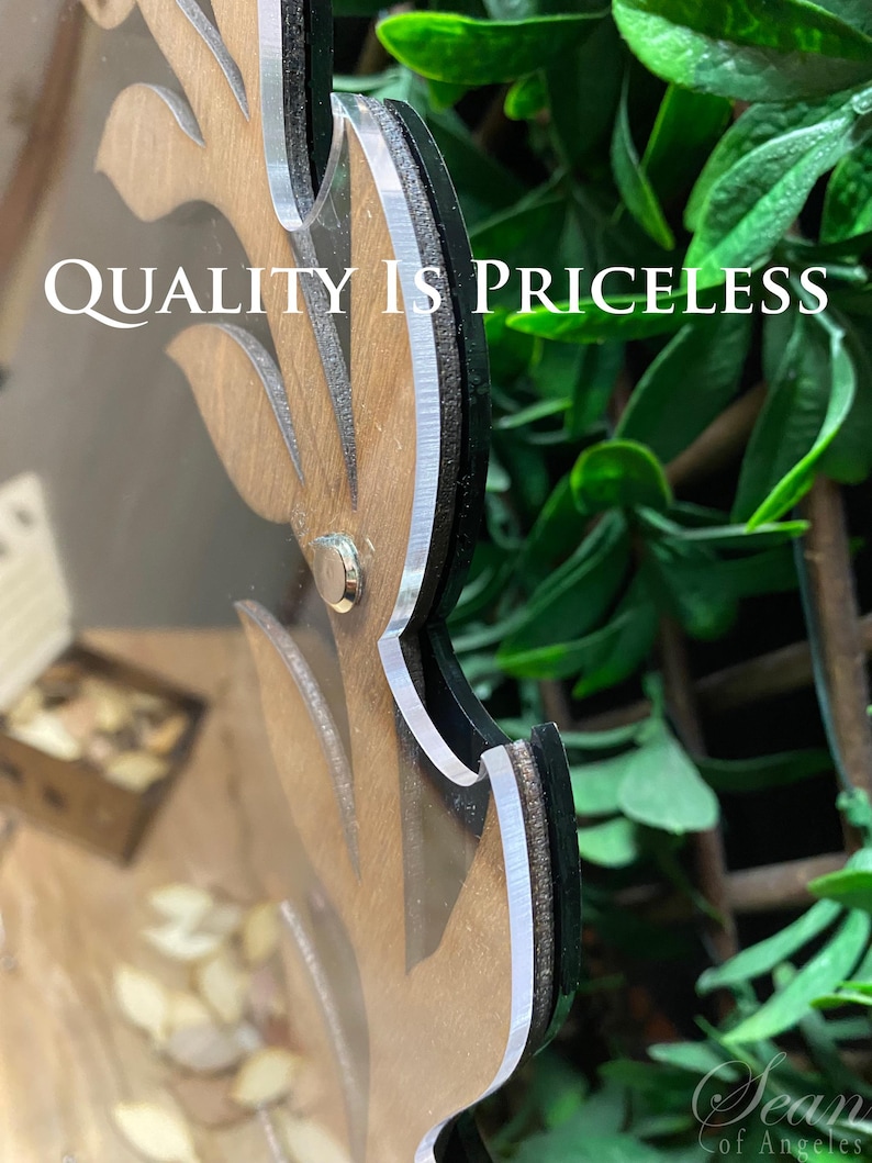 May include: A wooden sign with a leafy design and the text "QUALITY IS PRICELESS". The sign is framed with a black border and a silver trim.