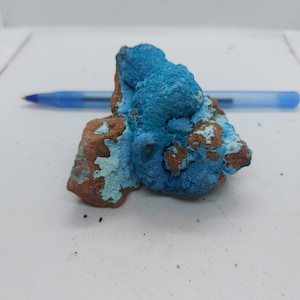 Può includere: Un masso ruvido di forma irregolare con un rivestimento minerale blu-verde. Il masso è principalmente marrone con macchie blu-verdi.