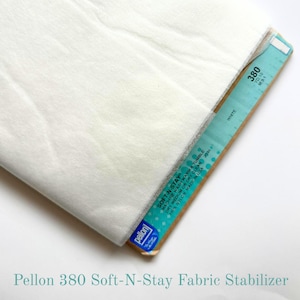 May include: A folded sheet of white Pellon 380 Soft-N-Stay fabric stabilizer. The product is wrapped around a cardboard core featuring teal and white branding with the text 380, White, and Soft-N-Stay, indicating 100% nylon material.