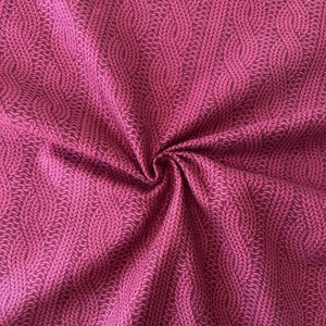 May include: A close-up of a pink fabric with a woven pattern of small, dark pink leaves. The fabric is folded and textured.
