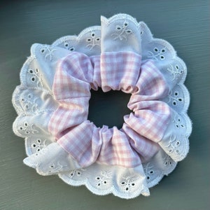 May include: A pink and white gingham hair scrunchie with white eyelet lace trim.