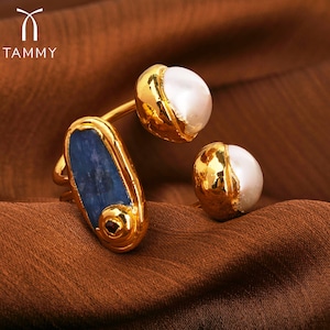 May include: Gold ring with a blue oval stone and two white pearl accents.