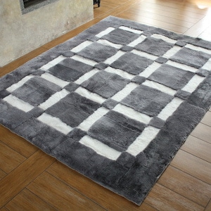 May include: A grey and white checkered area rug with a soft, fluffy texture. The rug has a geometric pattern of squares and rectangles.