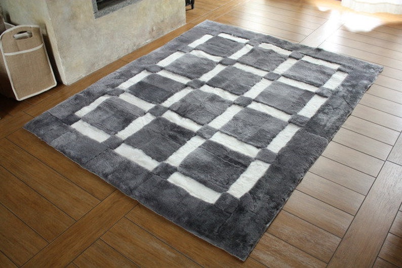 May include: A grey and white checkered area rug with a soft, fluffy texture. The rug has a geometric pattern of squares and rectangles.