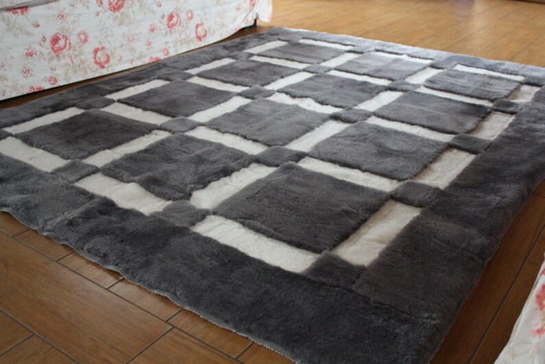May include: A grey and white checkered rug with a soft, fluffy texture. The rug has a geometric pattern with squares of grey and white.