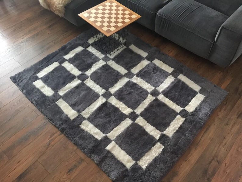 May include: A grey and white chequered rug with a soft, fluffy texture. The rug is made of sheepskin and has a modern design.