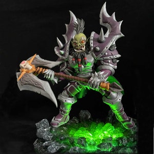May include: A green-skinned Orc warrior figurine with a large axe, wearing purple and silver armor with spikes. The figurine is standing on a base with green glowing crystals.