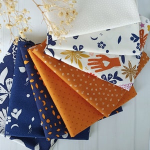 May include: A selection of patterned fabric squares in various designs and colours. The fabrics feature floral, hand, and geometric patterns in navy blue, orange, and white. The fabrics are arranged in a fan shape, showcasing the different designs.