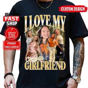 May include: Black t-shirt with a custom design featuring the text "I LOVE MY CHARLOTTE GIRLFRIEND" in gold lettering. The design includes a photo collage of six women with a lightning bolt background. The shirt also has "CUSTOM DESIGN" and "FAST SHIP" labels.