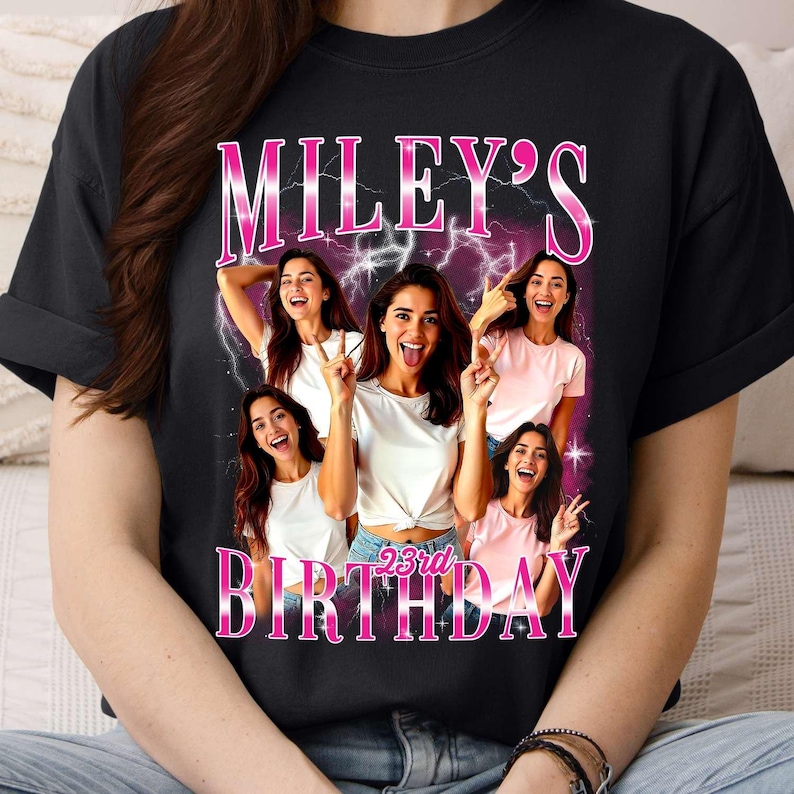 Puede incluir: Camiseta negra con un dise&ntilde;o que dice "MILEY'S 23rd BIRTHDAY". El dise&ntilde;o muestra a una mujer haciendo el signo de la paz y sacando la lengua, sobre un fondo de rayos rosas y morados.