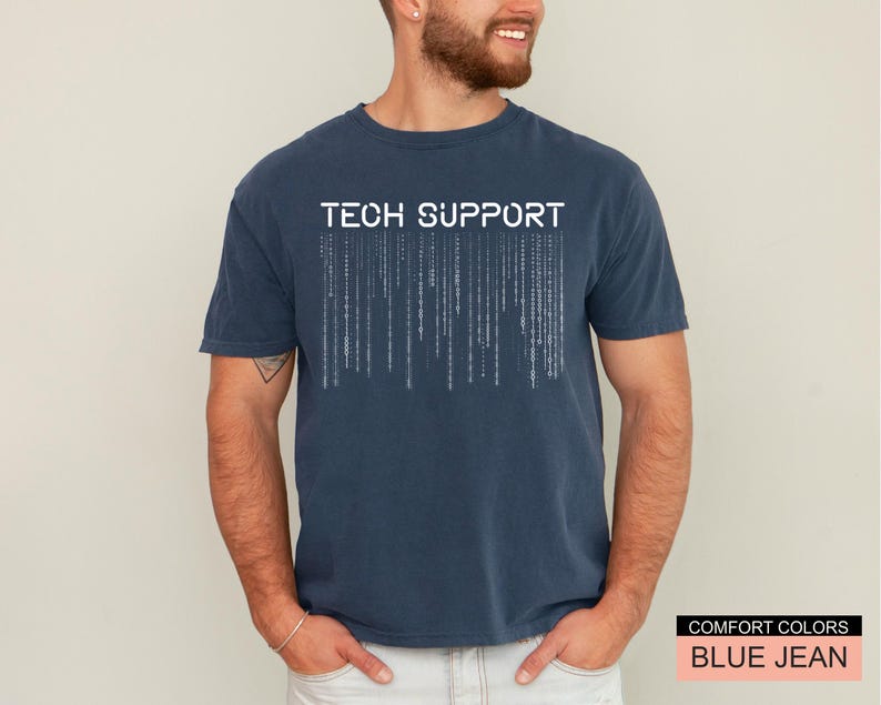 K&ouml;nnte beinhalten: Ein marineblaues T-Shirt mit den wei&szlig;en Worten "TECH SUPPORT" &uuml;ber einer Matrix-Grafik. Das Shirt ist von der Marke Comfort Colors in der Farbe "Blue Jean".