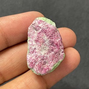 Peut inclure: Un spécimen minéral brut et non poli présentant un centre rose magenta vibrant avec une surface cristalline texturée, entouré d'une bordure distincte de matériau minéral vert citron pâle, illustrant des formations géologiques naturelles.