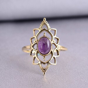 May include: A gold ring with a delicate, intricate design featuring a purple amethyst gemstone in the center.