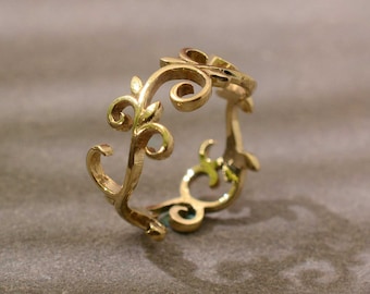May include: A gold ring with a delicate, intricate design of swirling vines and leaves.