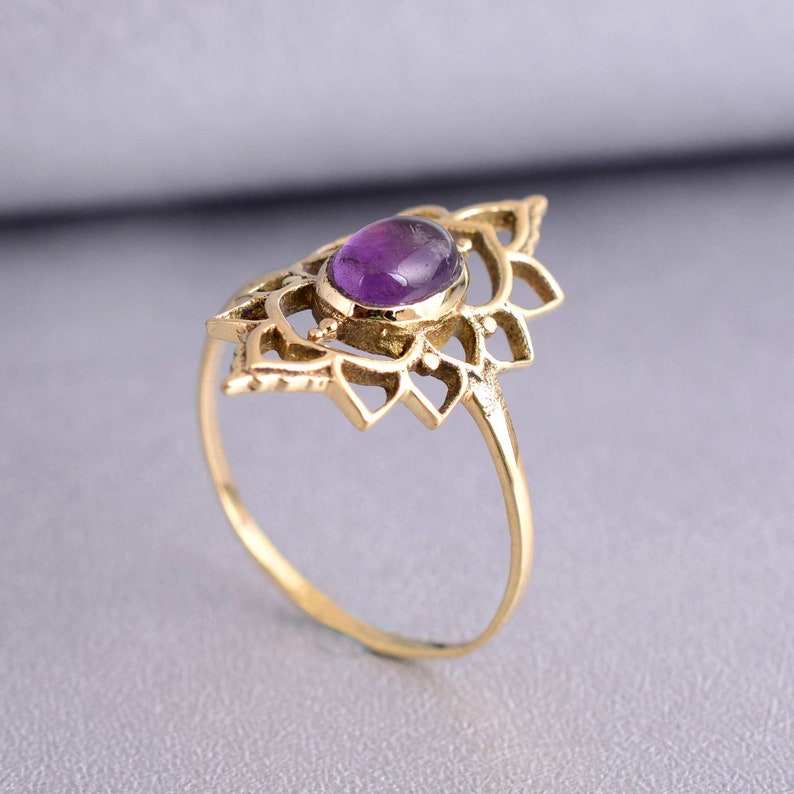 May include: A gold ring with a delicate, intricate design featuring a purple amethyst gemstone in the center.