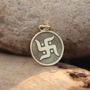 Op de afbeelding: Een gouden hanger met een swastika-symbool, een traditioneel hindoeïstisch symbool voor geluk en voorspoed.