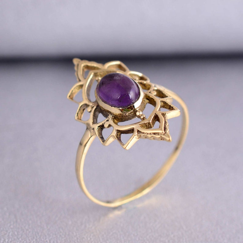 May include: A gold ring with a delicate, intricate design featuring a purple amethyst gemstone in the center.
