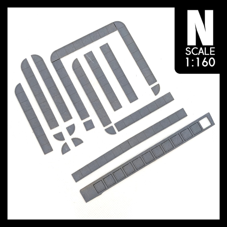 May include: A set of grey plastic model railway track pieces in N scale, 1:160 scale. The pieces include straight track, curved track, and a platform.