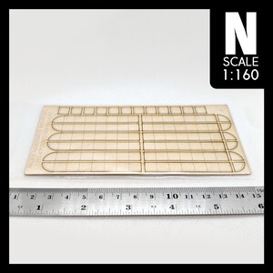 May include: A wooden model kit for a poured sidewalk, in 1:160 scale, from Pacific Northwest Miniatures. The kit includes a sheet of pre-cut wood pieces with a grid pattern and rounded edges.