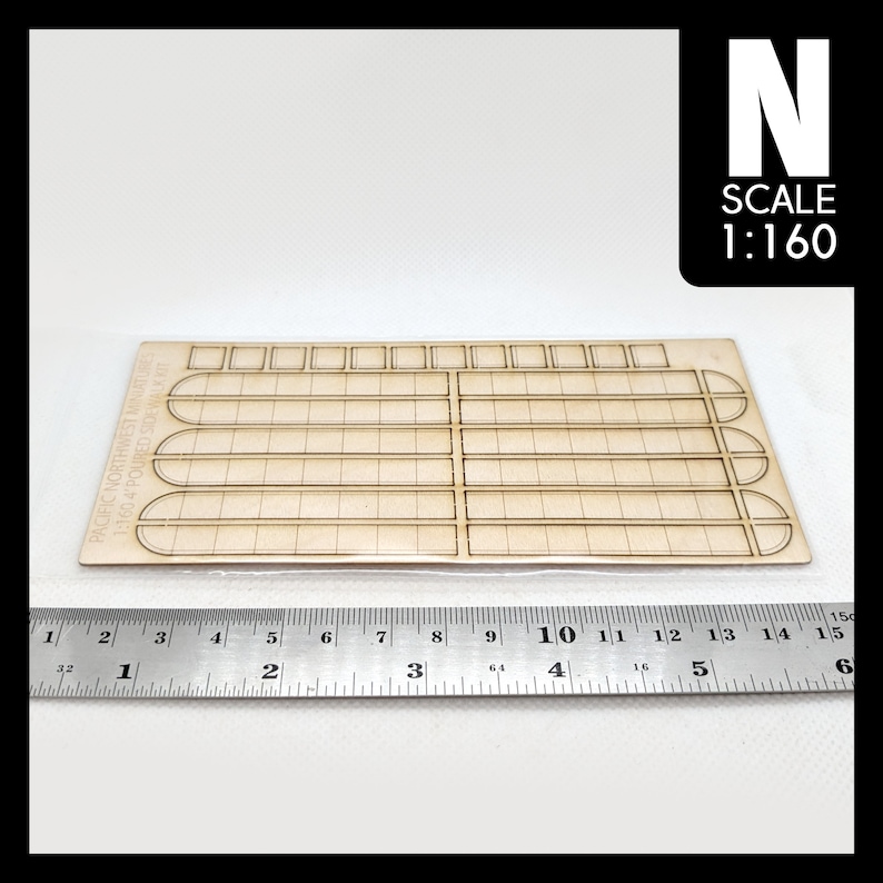 May include: A wooden model kit for a poured sidewalk, in 1:160 scale, from Pacific Northwest Miniatures. The kit includes a sheet of pre-cut wood pieces with a grid pattern and rounded edges.