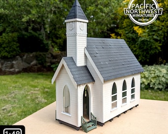 May include: A miniature church model with a white exterior, grey roof, and a steeple. The model has arched windows and a small green porch. The text "STRUCTURE KIT No. 11 - Church" is displayed below the model, along with a "1:48 SCALE" label.
