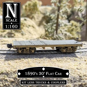 May include: A model of an 1890s 30-foot flat car, N scale 1:160, with a weathered wooden deck. The model train car is on a track, with text that reads "KIT LESS TRUCKS & COUPLERS".