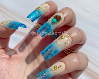 Uñas postizas 3D con diseño de tortuga marina, puntas degradadas en azul y detalles de conchas marinas.