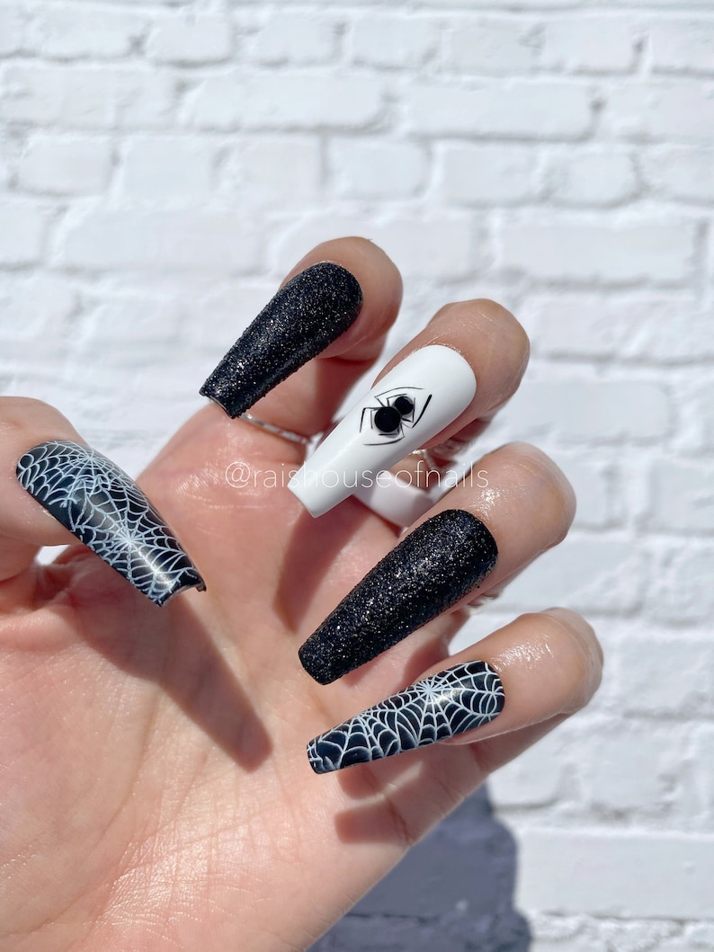 Uñas postizas de Halloween con diseño de telaraña, purpurina negra y arte de telaraña.