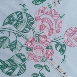 Très belle nappe rectangulaire ancienne entièrement brodée à la main.

Ses broderies sont très denses, de jolies couleurs pastelles,
 un mélange de fleurs stylisées et de motifs géométriques typiques de l'art déco. 

Elle est monogrammée au centre AP