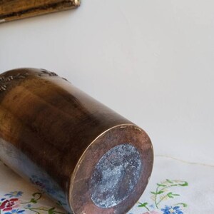 Op de afbeelding: Een vintage messing vaas met een reli&euml;f van een bloemenmotief. De vaas heeft een ronde basis en een licht uitlopende bovenkant.