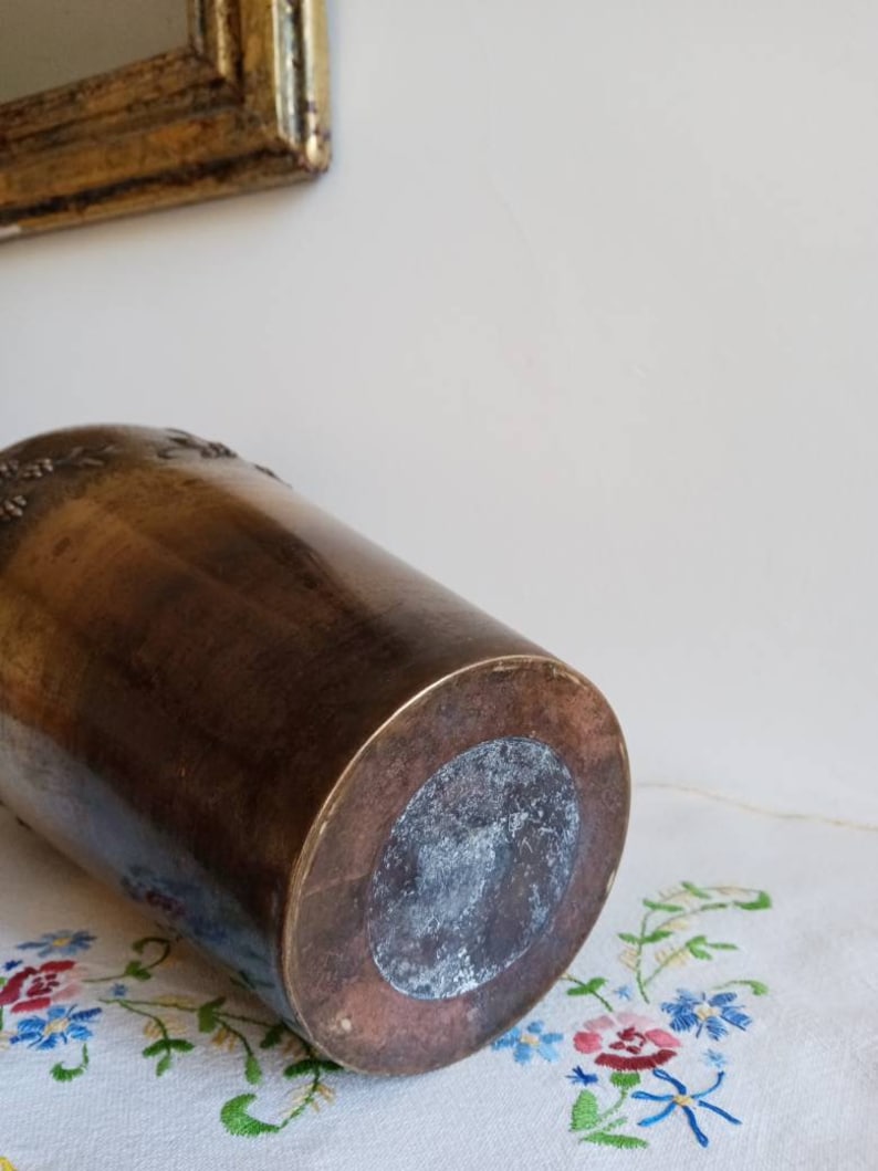 Op de afbeelding: Een vintage messing vaas met een reli&euml;f van een bloemenmotief. De vaas heeft een ronde basis en een licht uitlopende bovenkant.