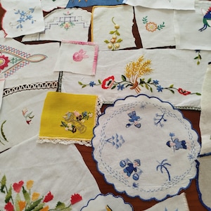 Può includere: Una collezione di quadrati e cerchi di tessuto bianco e colorato con vari motivi ricamati di fiori, grano e figure umane. I pezzi presentano bordi smerlati, finiture in pizzo e fili colorati nelle tonalità del rosso, blu, giallo e verde.