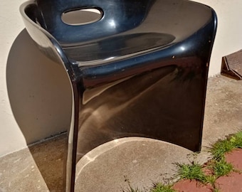 Könnte beinhalten: Ein schwarzer Plastikstuhl mit einem einzigartigen, geschwungenen Design. Der Stuhl hat einen einzigen Ausschnitt auf der Sitzfläche.