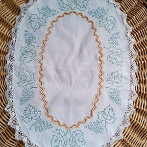 Oval hand-embroidered doily decorated with grapes and vine leaves