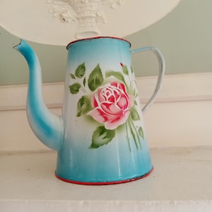 Coffee pot in enameled metal with flowers and rose decoration on a blue background
