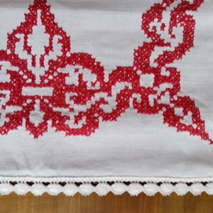 May include: White linen tablecloth with a red embroidered floral design and a white crocheted border.
