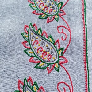 May include: White fabric with a red, green, and gray paisley embroidery design. The paisley design is repeated three times down the fabric.