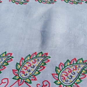May include: White fabric with a red, green, yellow, and gray embroidered paisley pattern.