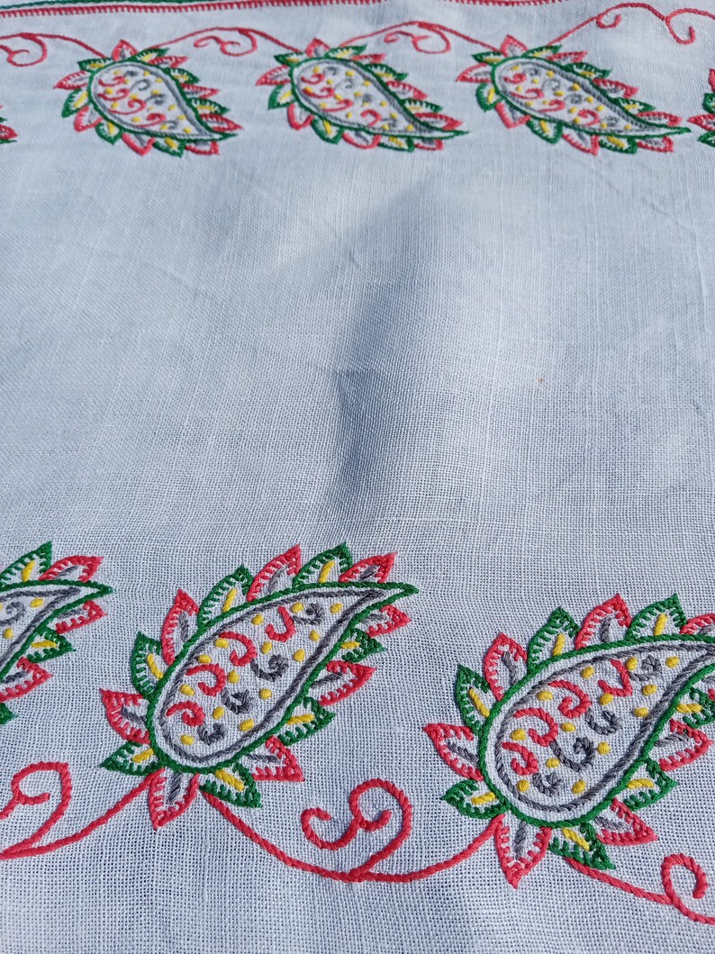 May include: White fabric with a red, green, yellow, and gray embroidered paisley pattern.